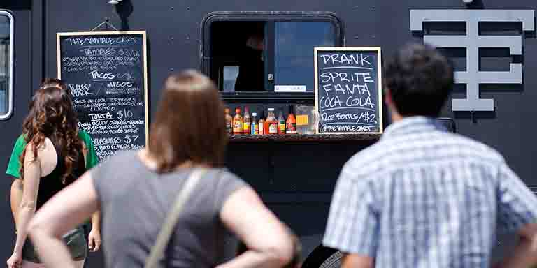 People look at the menus at a food truck.