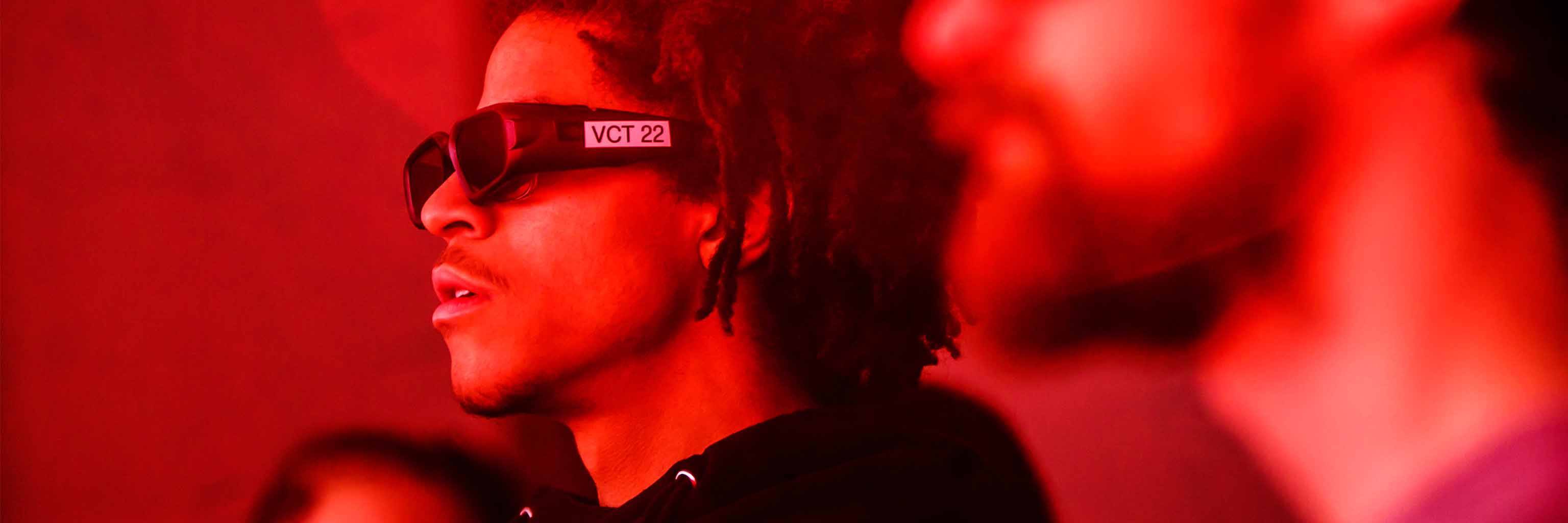 A student wears special glasses to look at something in a red-tinted room.