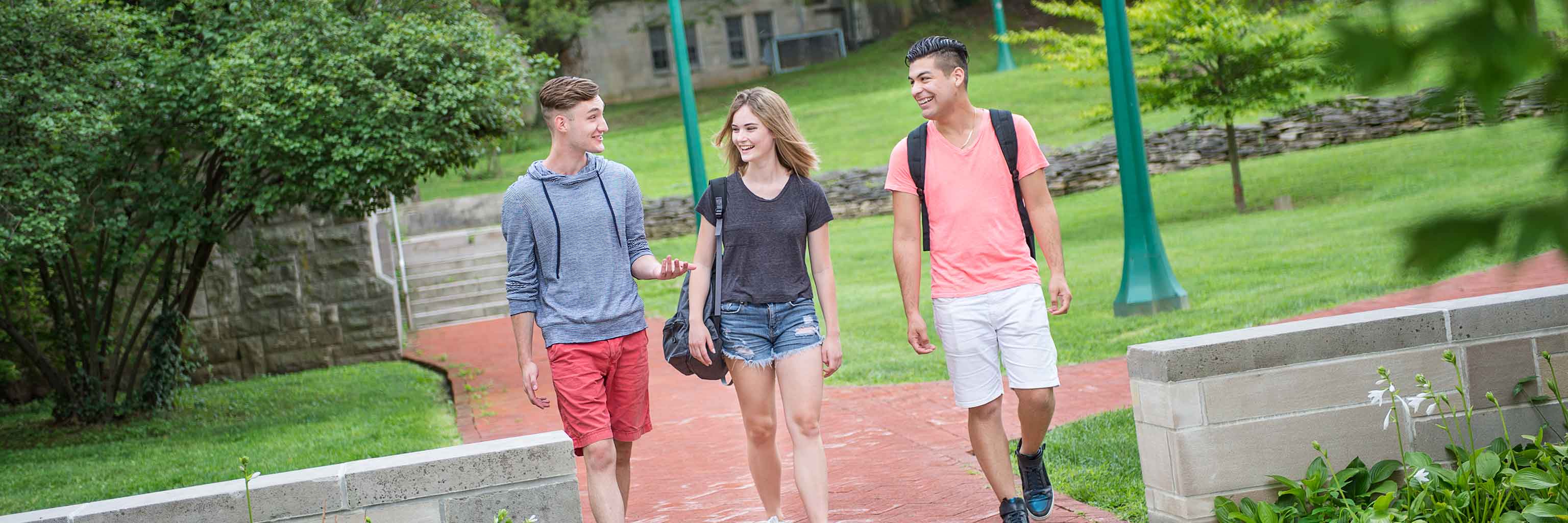 Three students walking side-by-side on campus