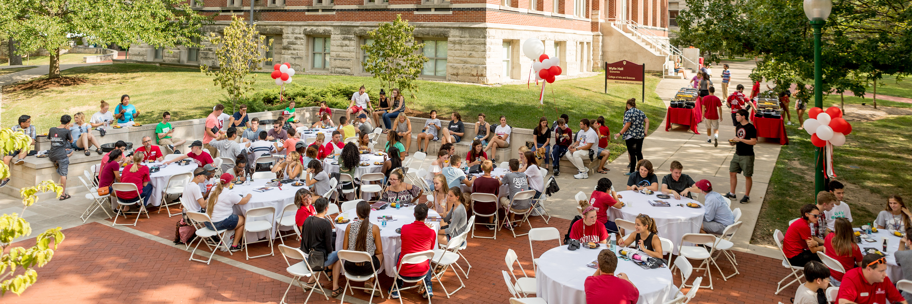 Students and College staff enjoying a meal together at tables outside.