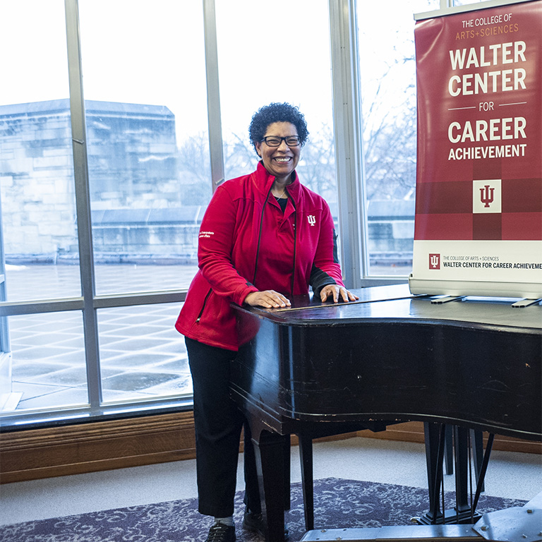 Marcia Debnam posing by a piano at a Walter Center event. 